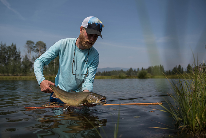 Frederik Lorentzen Fly Fishing Angler wears Fortis Eyewear releasing big brown trout
